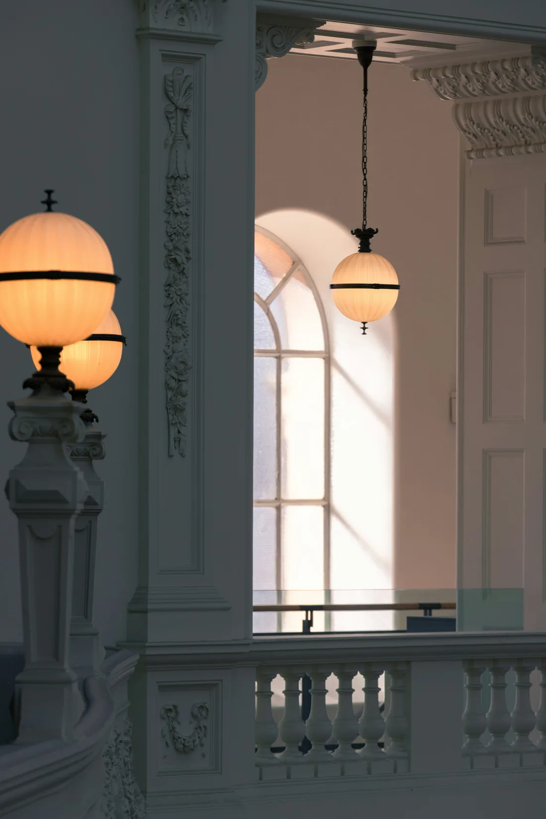 Deux luminaires anciens en verre opalin devant une fenêtre à petits bois