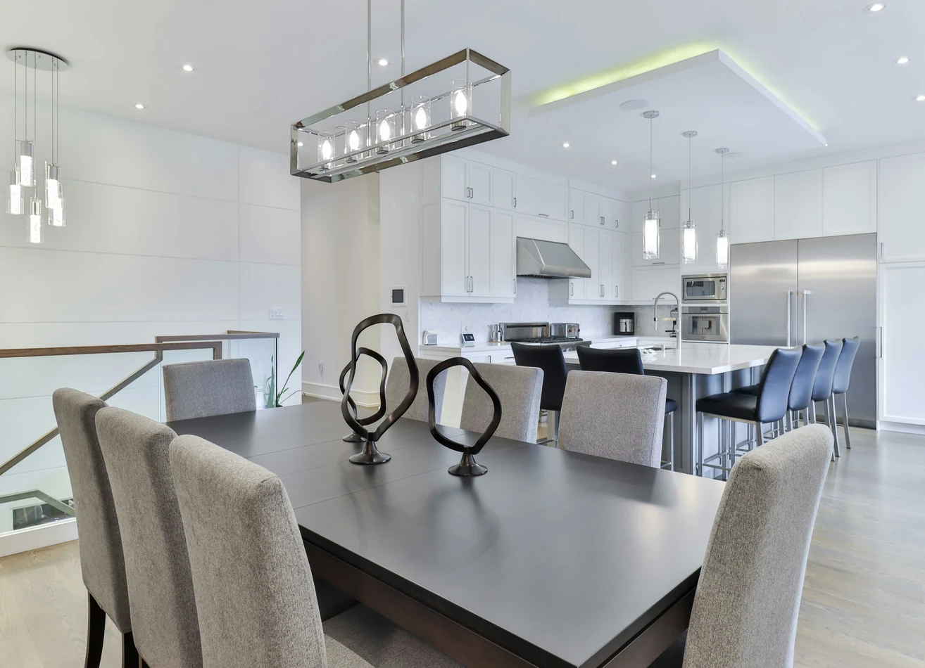 Salle à manger ouverte sur la cuisine, suspension linéaire au-dessus de la table et pendants sur l'îlot