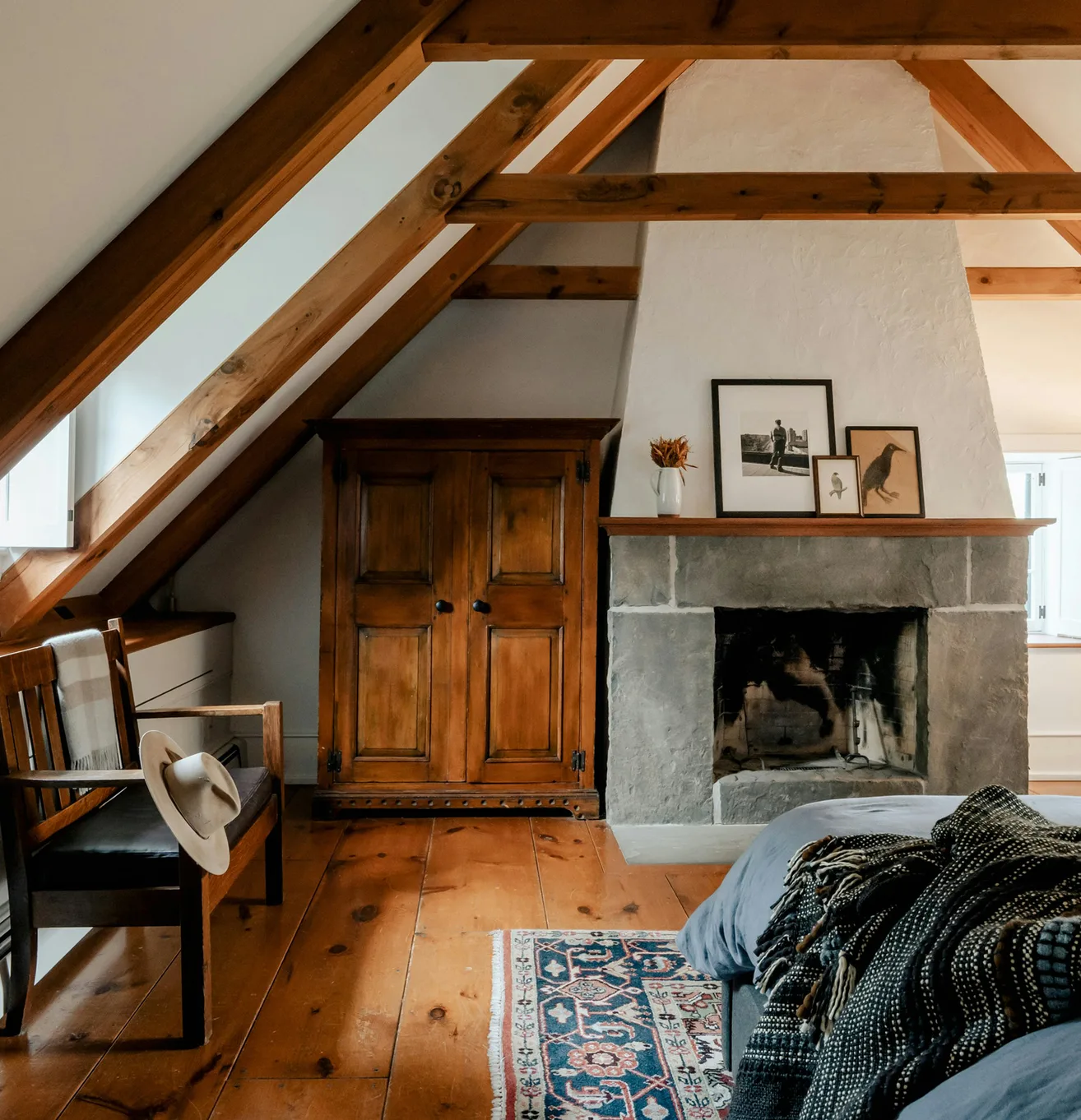 Chambre sous combles d'une maison ancienne, charpente apparente, cheminée de pierre et parquet